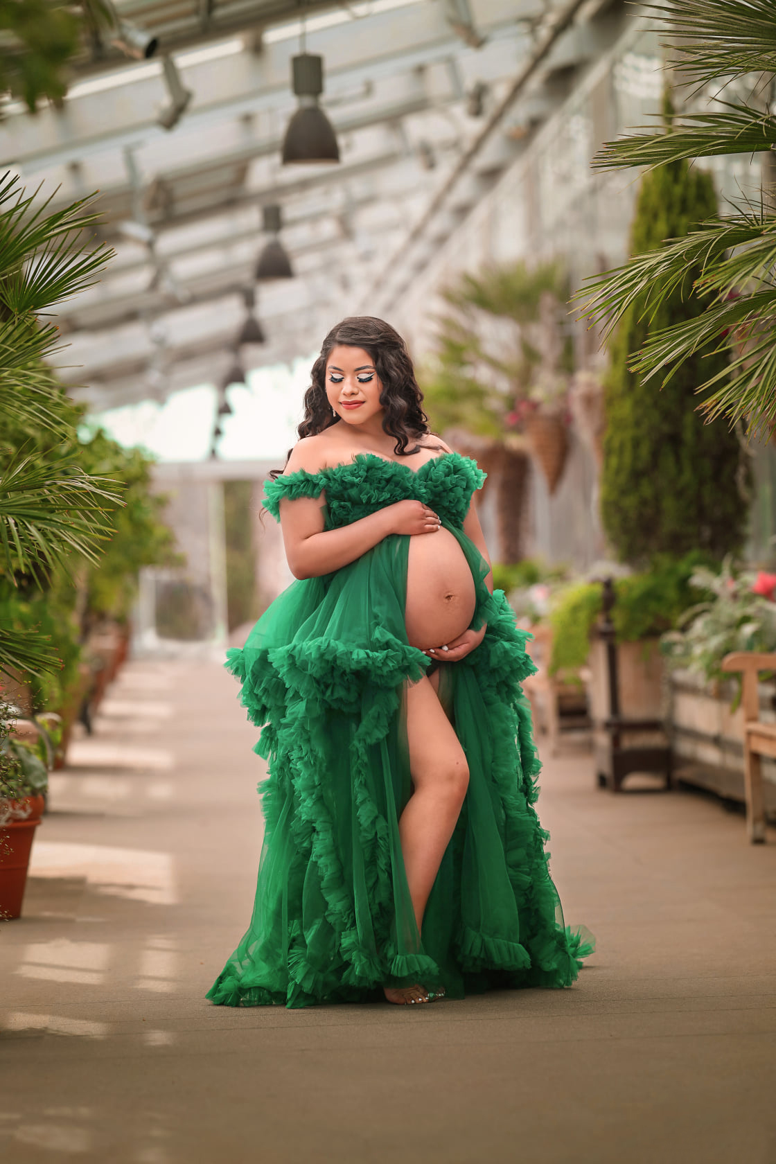 Gorgeous pregnant woman in a green flowy dress at the Botanical Gardens in Denver after her Aurora midwives appointment.