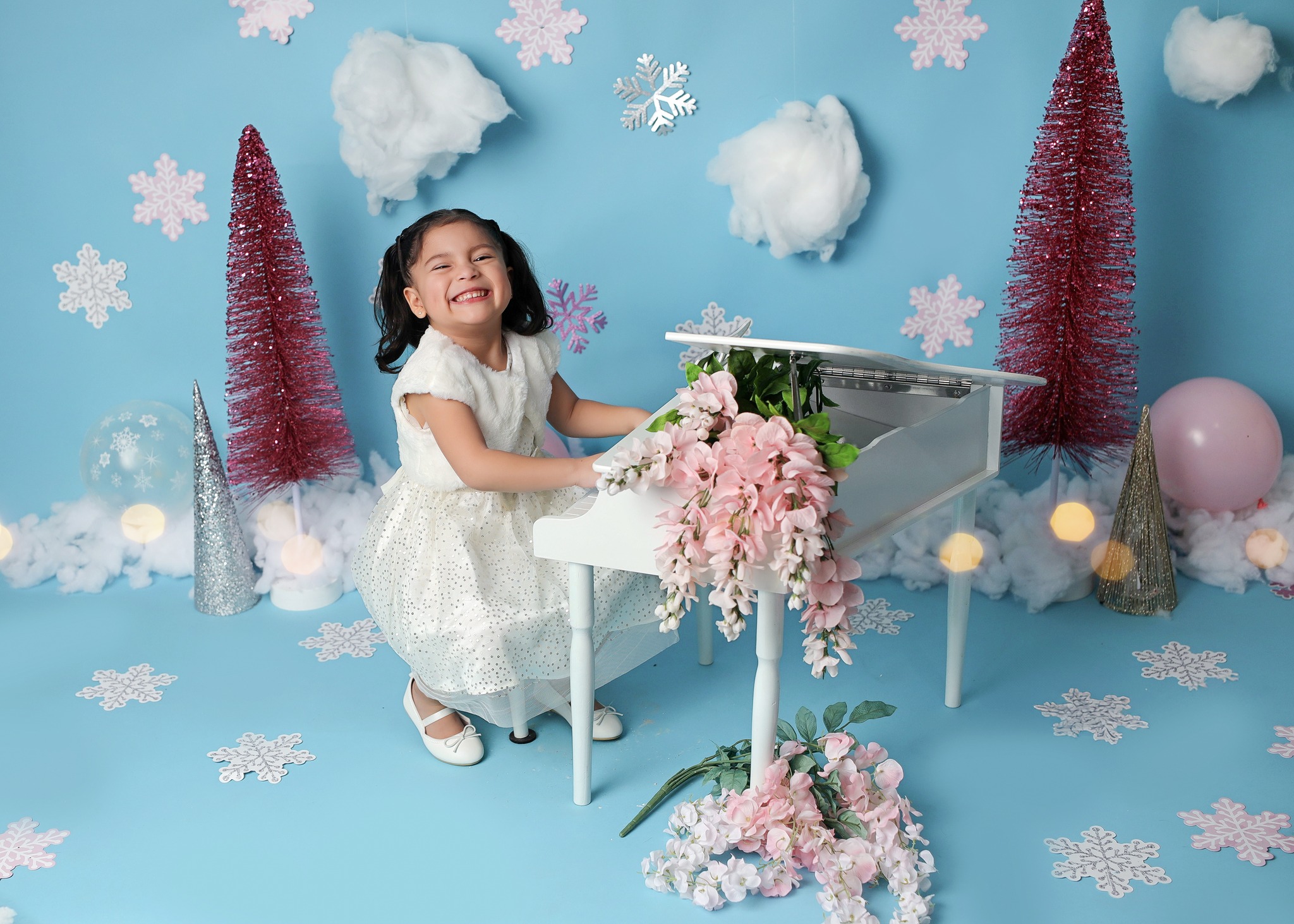 Sweet child session with winter wonderland backdrop and young lady playing mini piano.