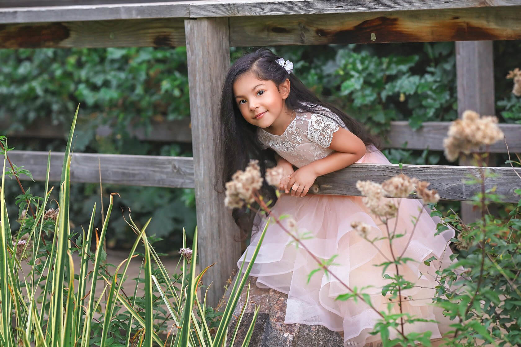 Sweet Denver Childrens photography session of young girl posing in pretty dress through fence posts. Add this to the list of things to do in Boulder with kids.