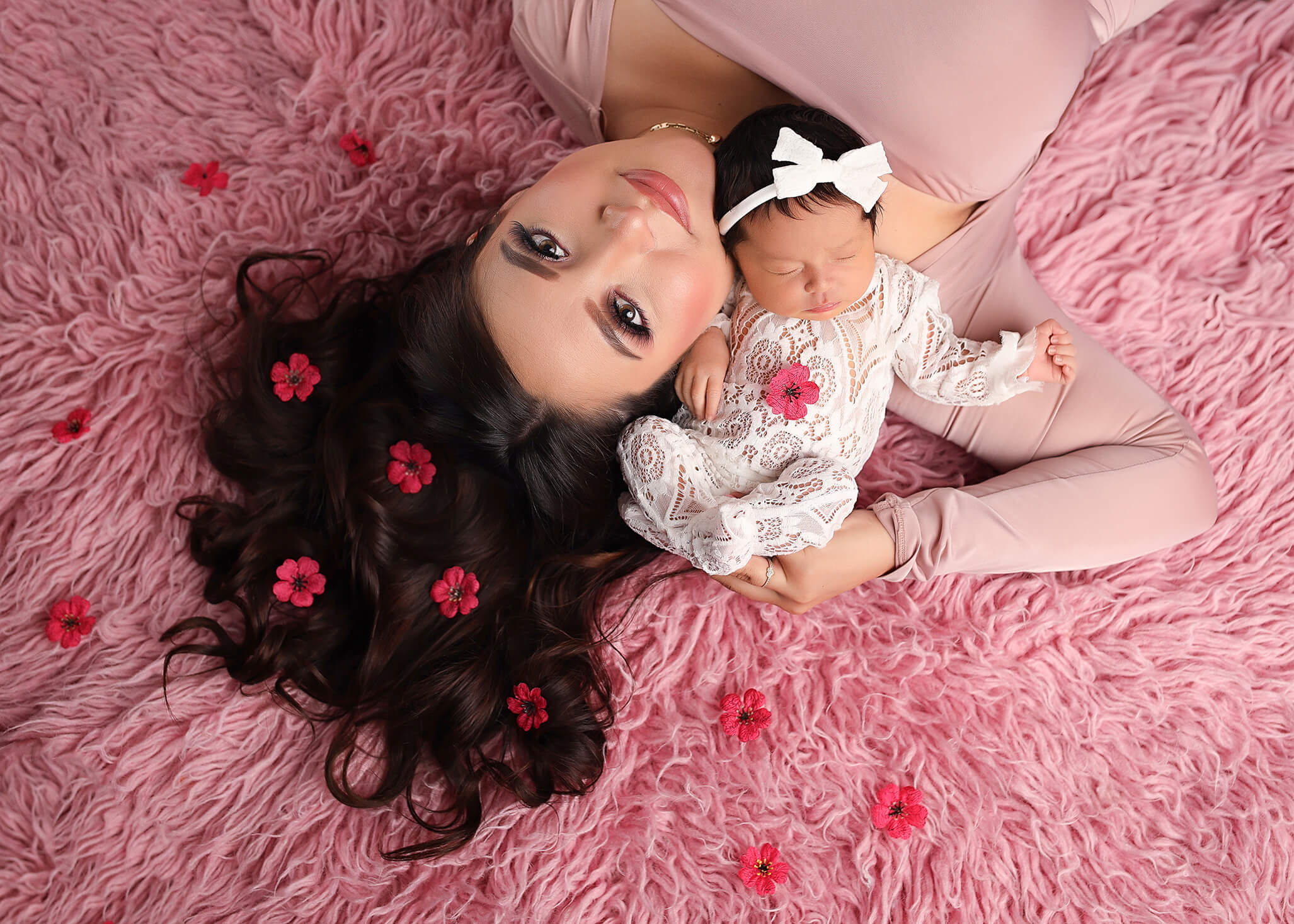 Baby and momma lying together on pink blanket cuddling together.