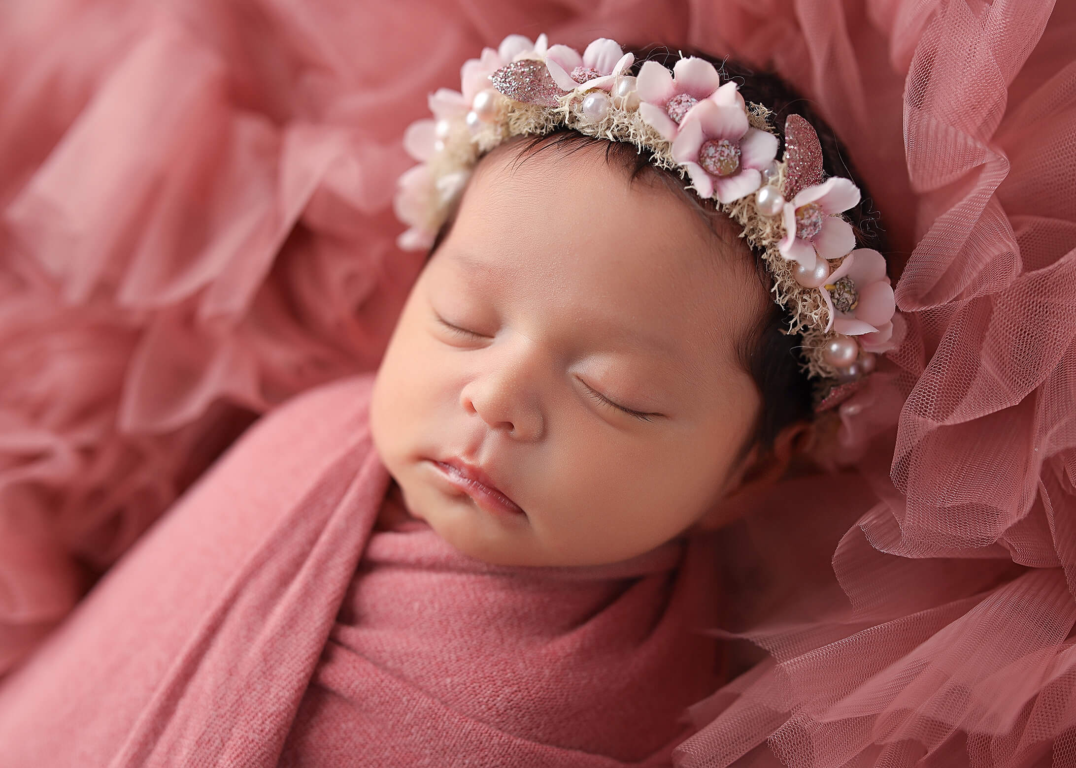 Beautiful baby posing in blush wrap sound asleep at her denver newborn photography session.