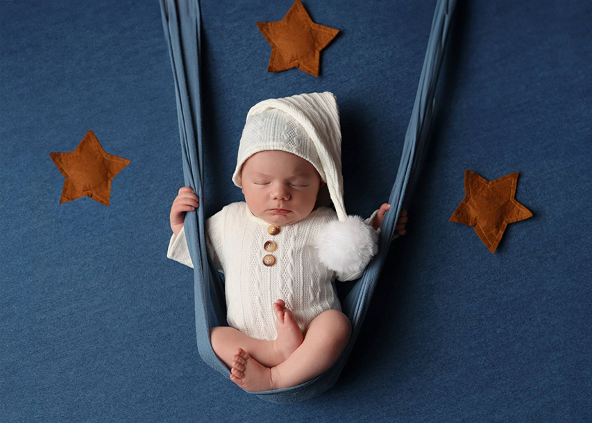 Cute baby sleeping on blue blanket and swinging on a dark blue wrap. 