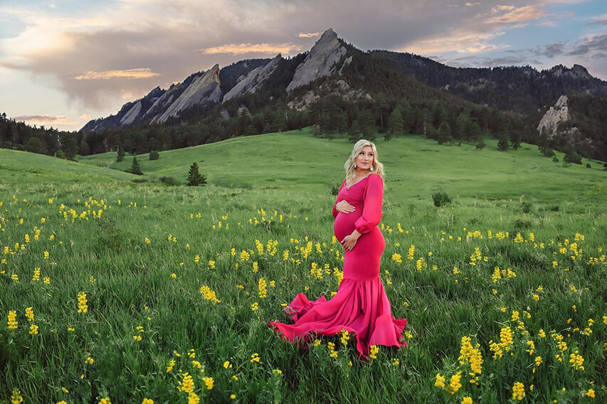 Momma to be posing in tight pink dress in the yellow flowers at Chatauqua Park in Boulder, Colorado.