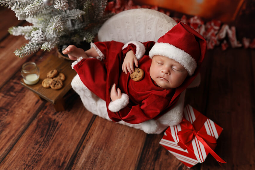 Sleeping baby dressed at santa clause eating milk and cookies. 