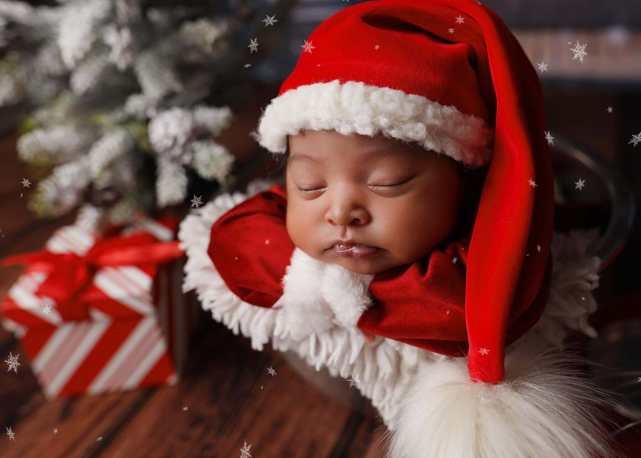 Adorable newborn baby sleeping in Santa costume posing at his Denver newborn photography session.