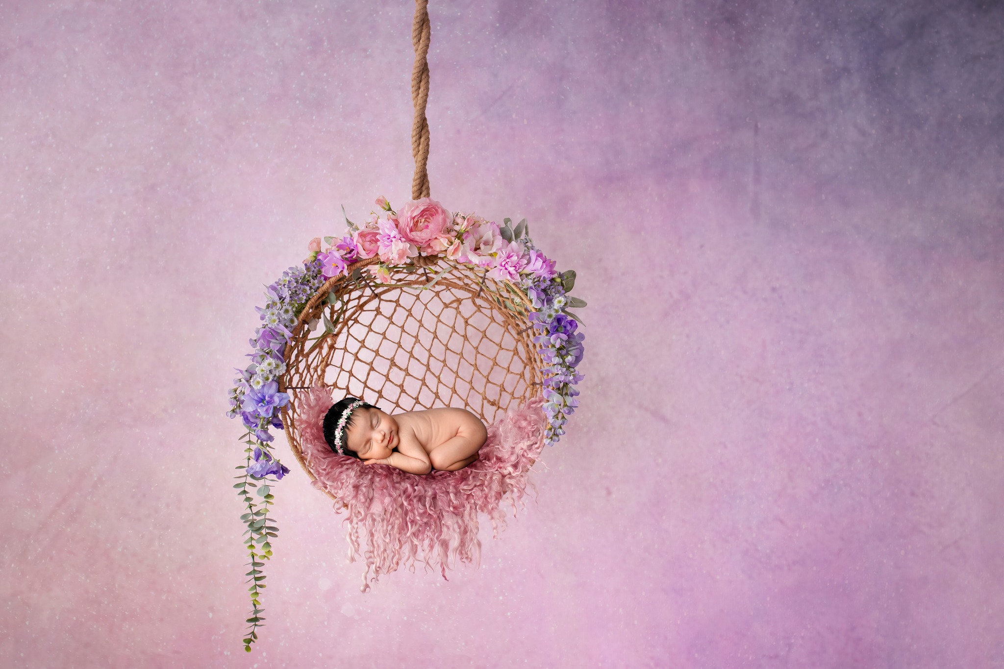 Newborn baby posing in beautiful floral hoop swing. Mom came from the Denver baby boutique.