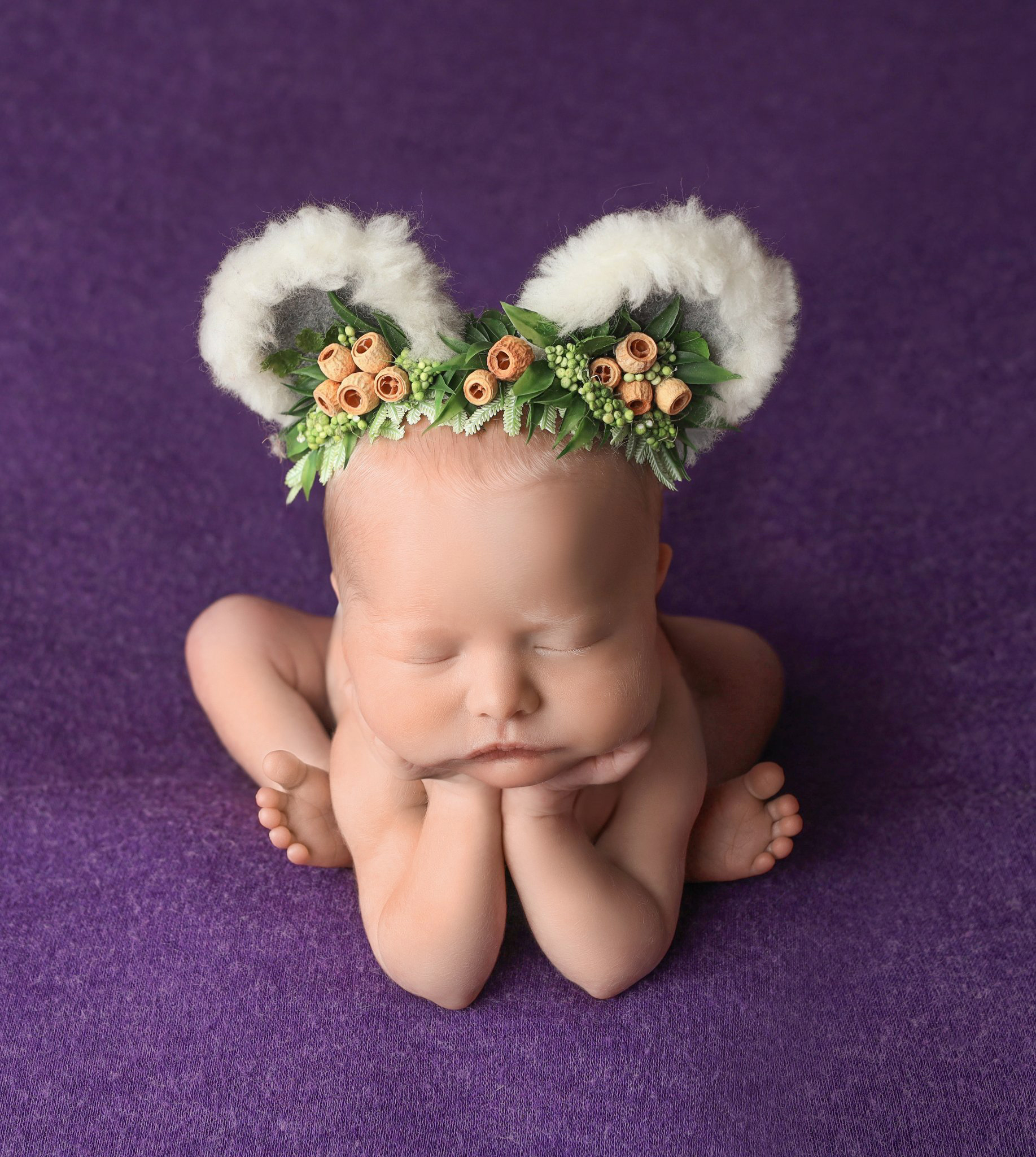 Cute newborn baby posing on a deep purple bean bag blanket after their Denver birth center appointment.