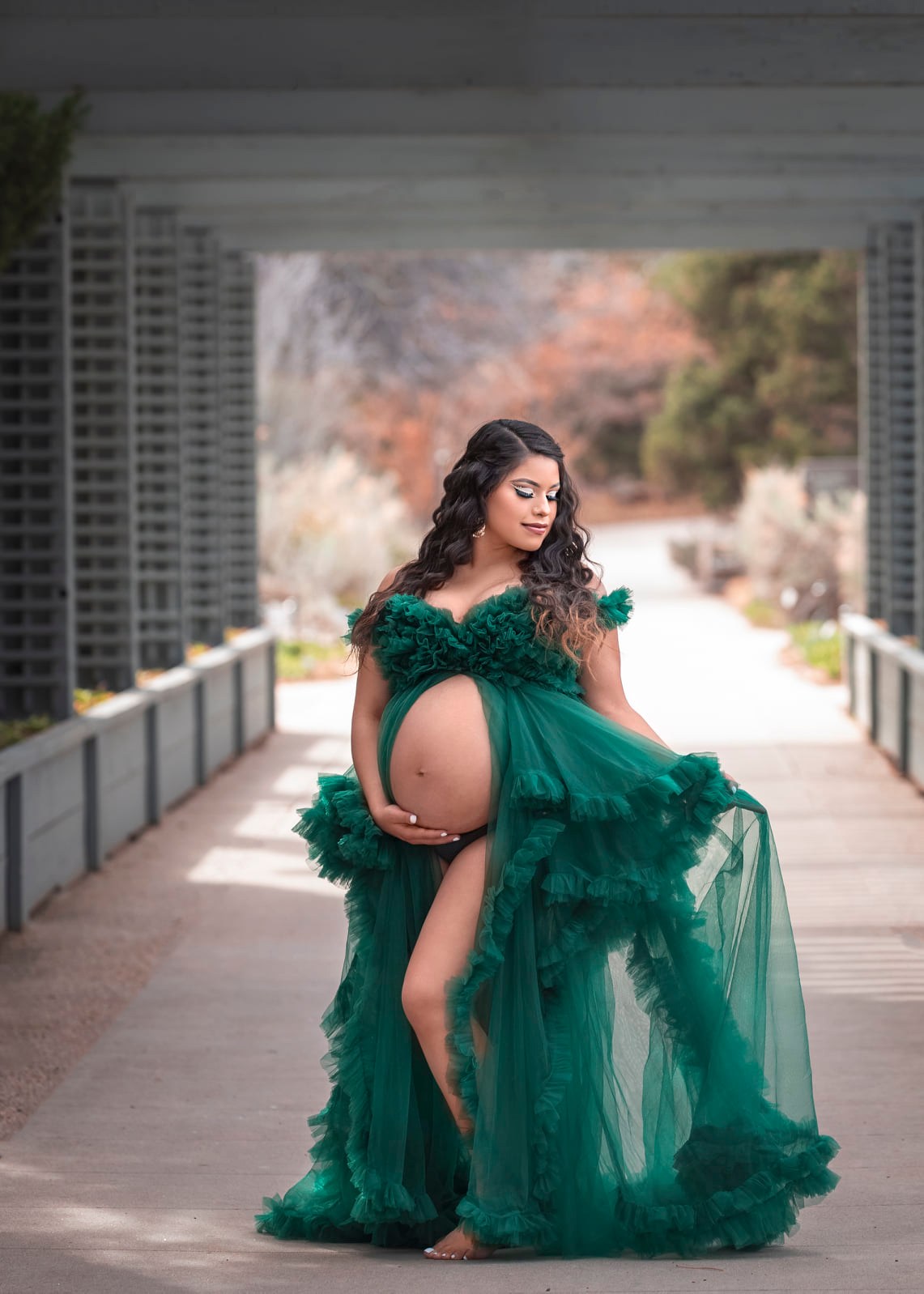 Future momma posing in her forest green maternity dress at the botanical gardens in Denver, Colorado.