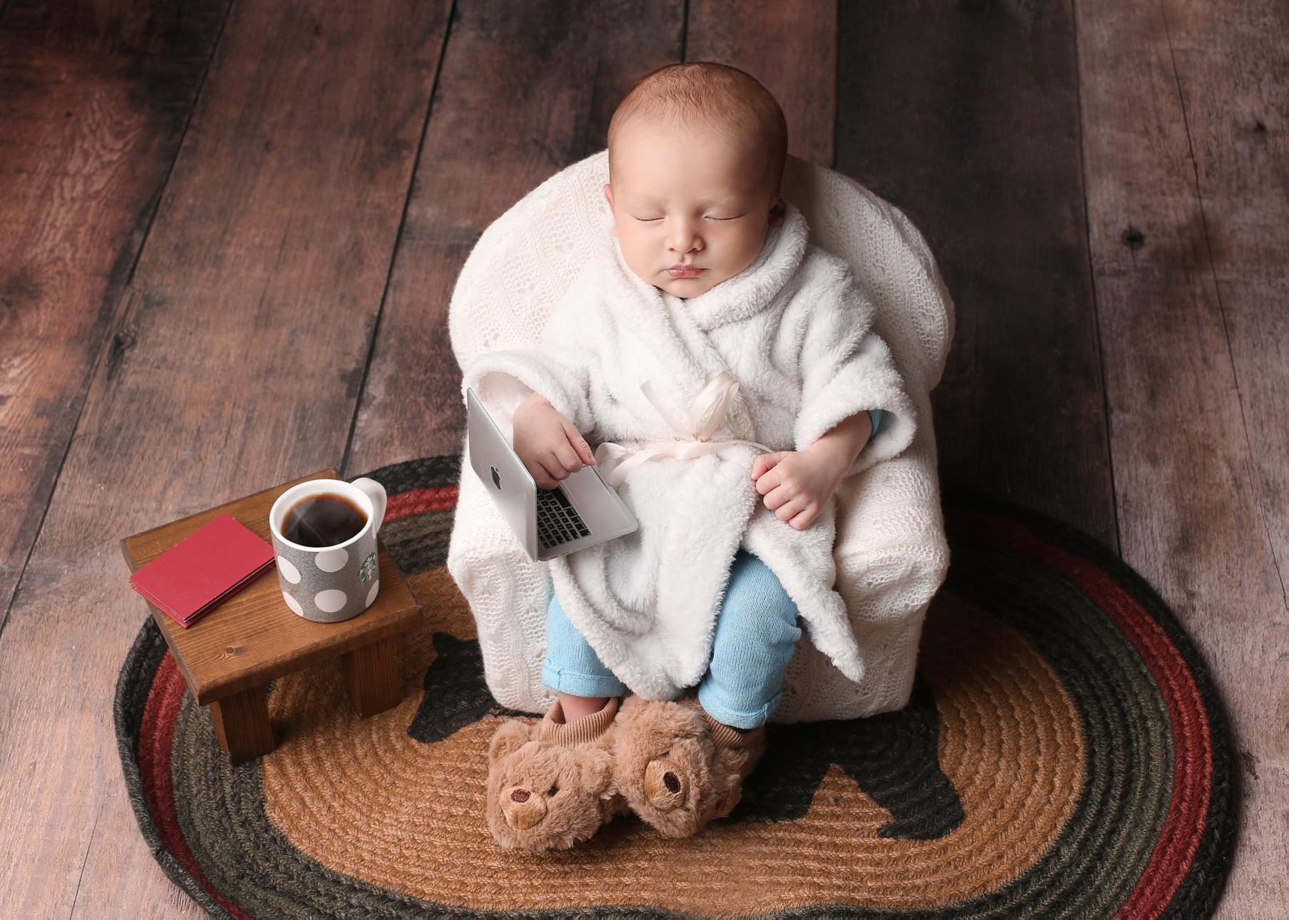 Sleeping newborn in a white robe enjoying his morning coffee.